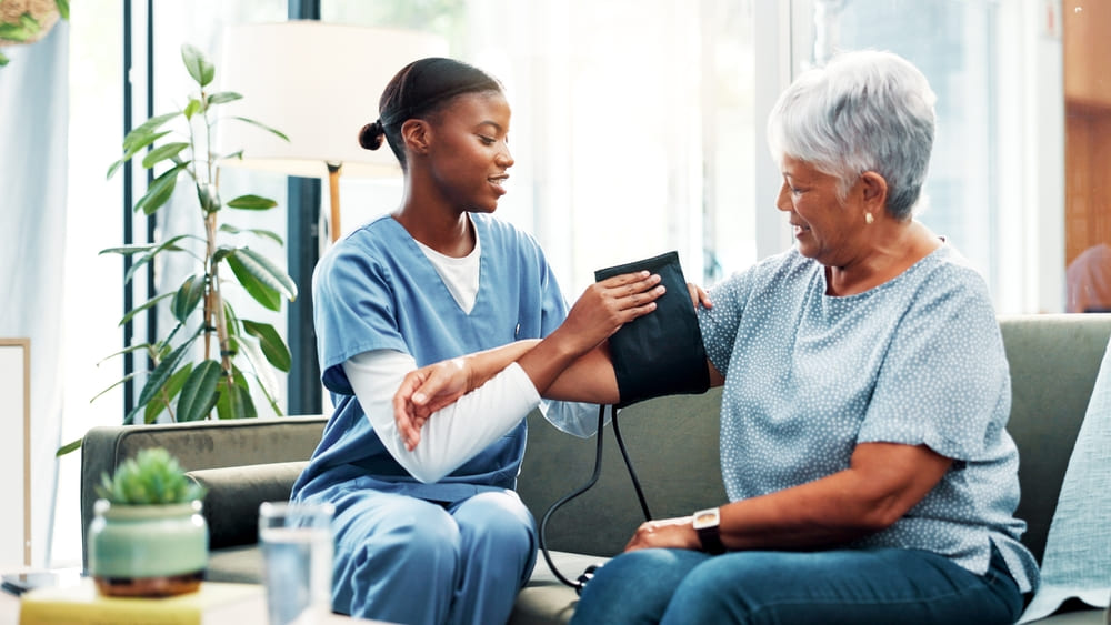Nurse checking senior woman's blood pressure during primary care visit focused on managing mild hypertension.