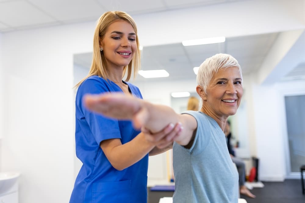 Smiling healthcare provider assisting senior woman during routine physical exam to promote preventive care and wellness