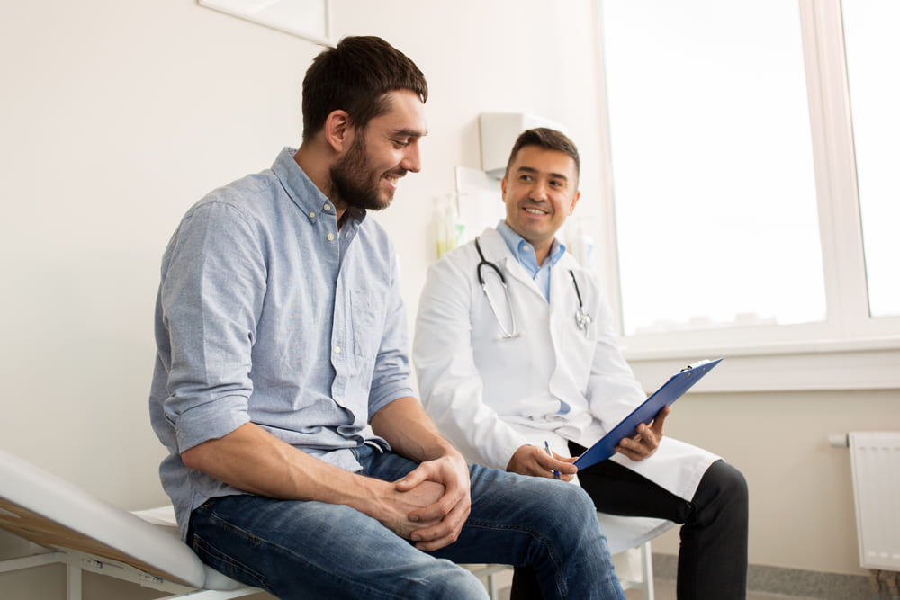 Male patient discussing prostate, testicular, and heart health screenings with doctor during medical consultation in clinic